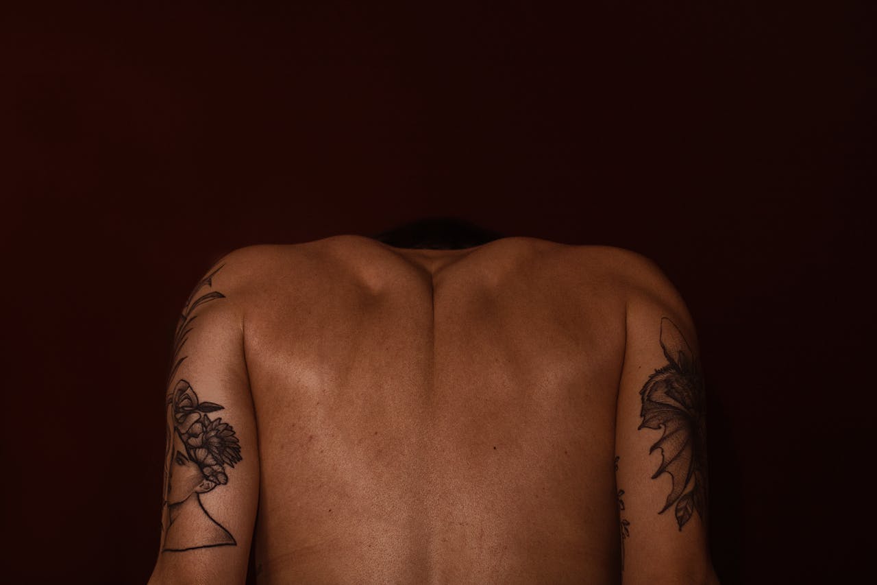 Artistic depiction of a tattooed mans back against a dark background.