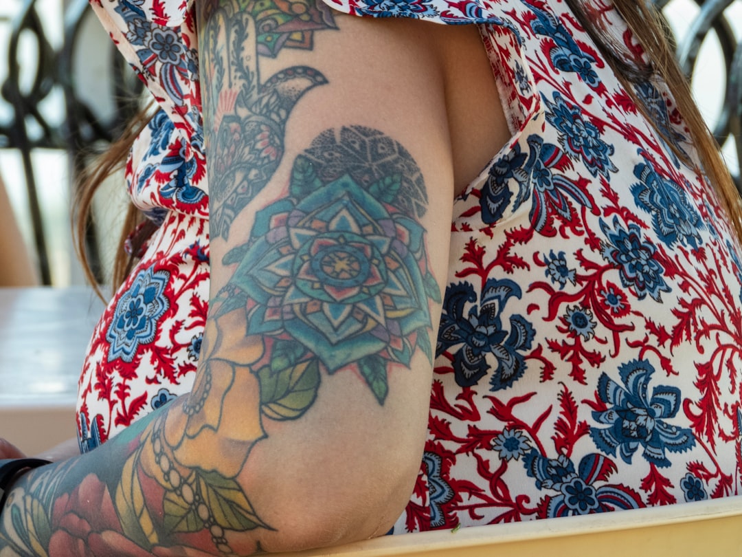 woman-wearing-red-blue-and-white-floral-top-with-multicolored-flower-arm-tattoo-0vbt-wbpihy